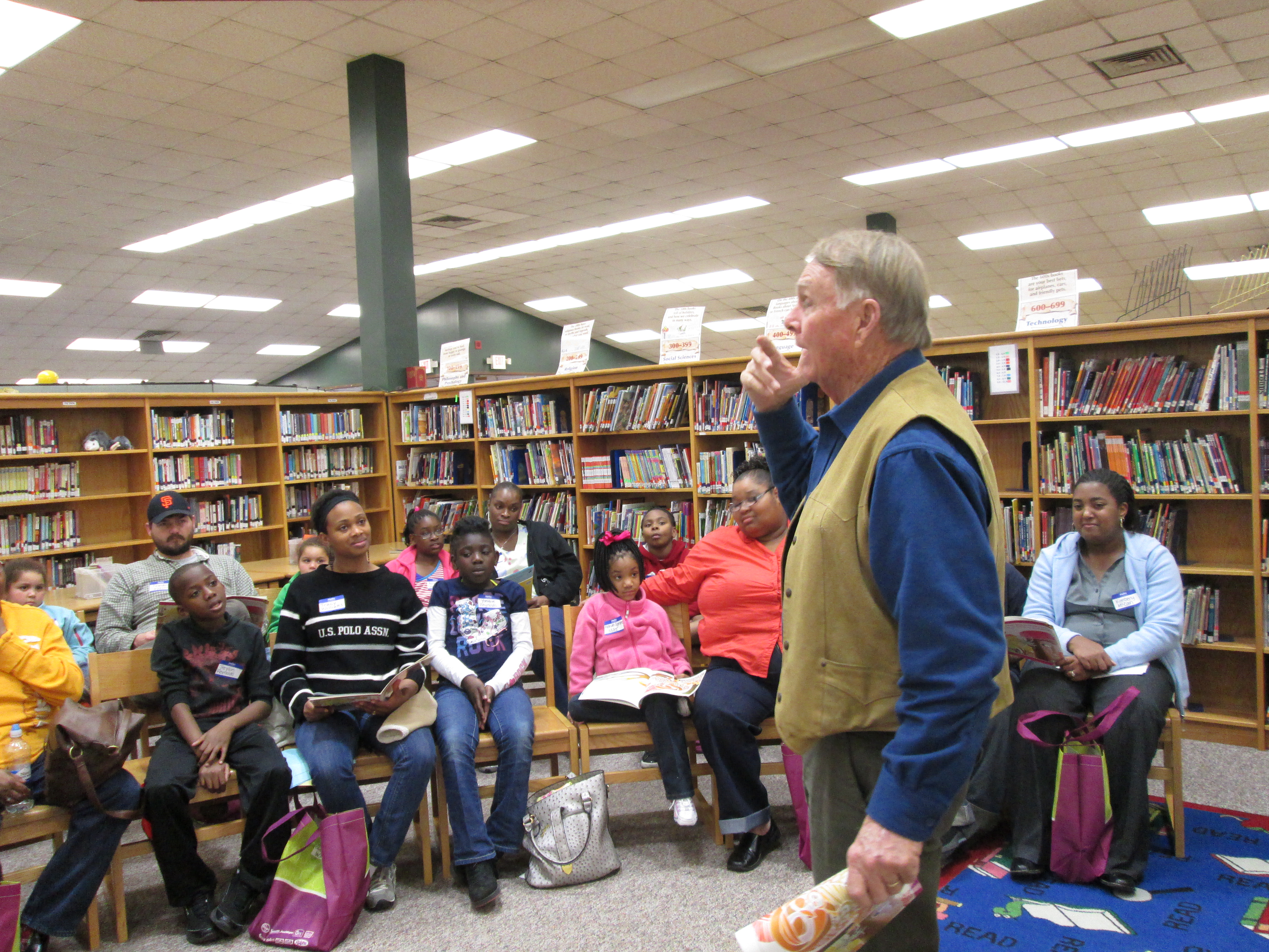 Photo: Storyteller, Robert “Uncle Bob” Neill, leads the families in reading Why Mosquitoes Buzz in Peoples’ Ears by Verna Aardema. 
